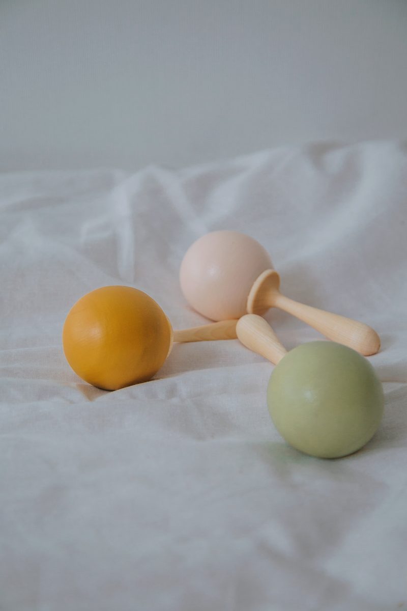 Three wooden ball rattles resting on a white sheet