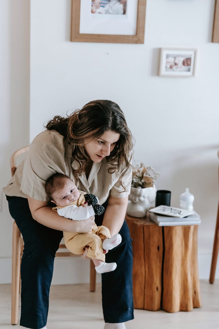 A mother holding her baby up in the air in a bright living room